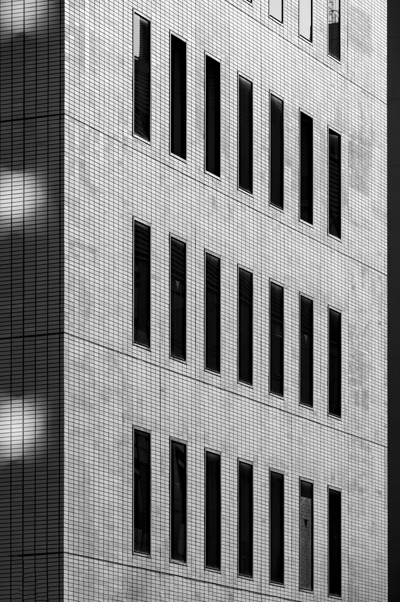 A tiled facade with rows of narrow vertical windows