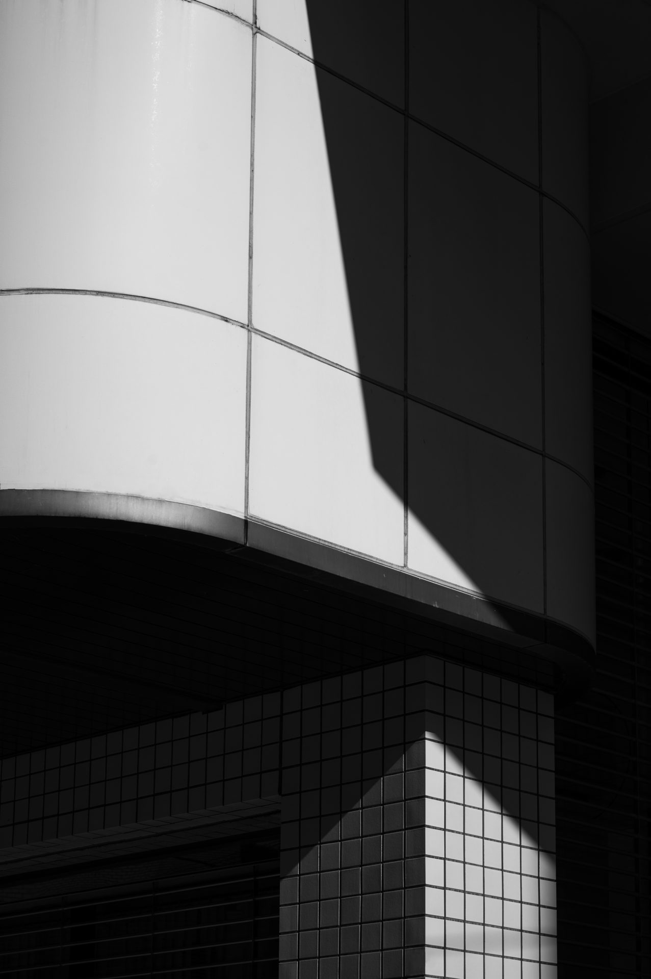 A curved tiled building edge in strong light and shadow