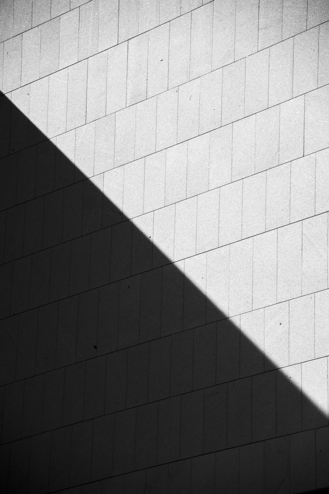A tiled facade cut diagonally by sunlight and shadow